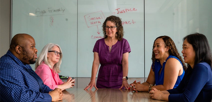 Researchers share a conversation around a conference room table.