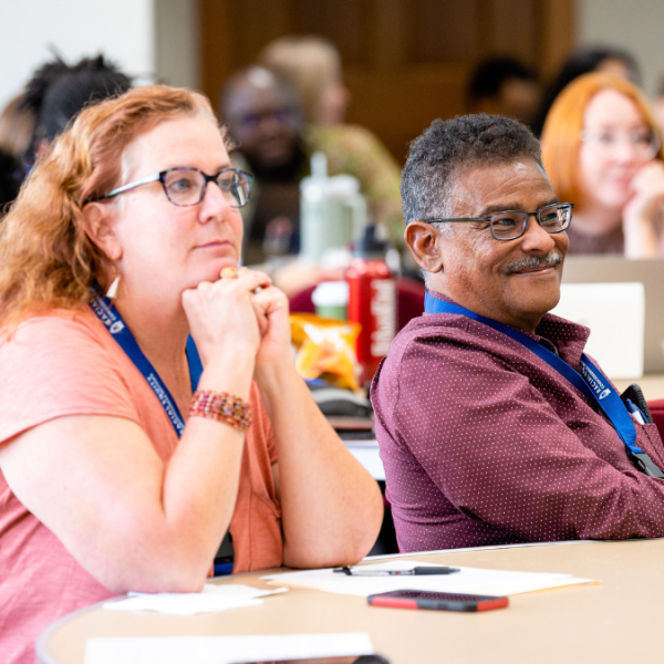 Two Pitt faculty listening to a speaker