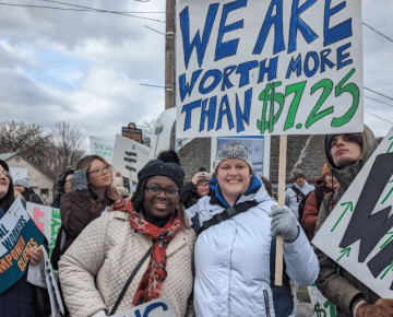 Two individuals with picket signs promoting pay equity for social workers in Harrisburg