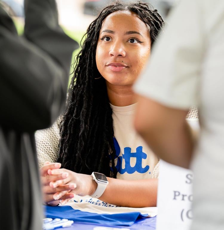 A Pitt volunteer talks with people.